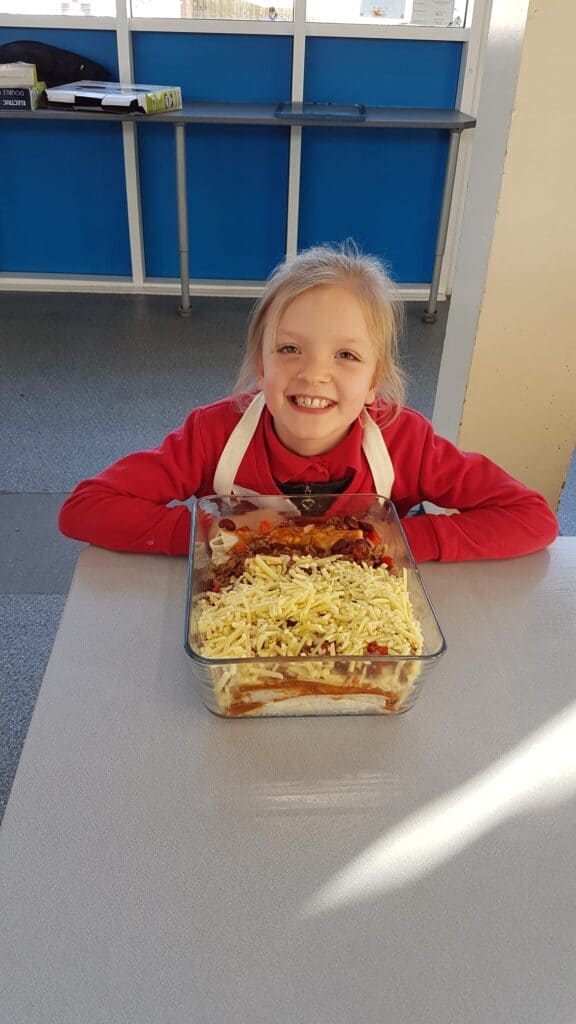 Child smiling with beef enchiladas
