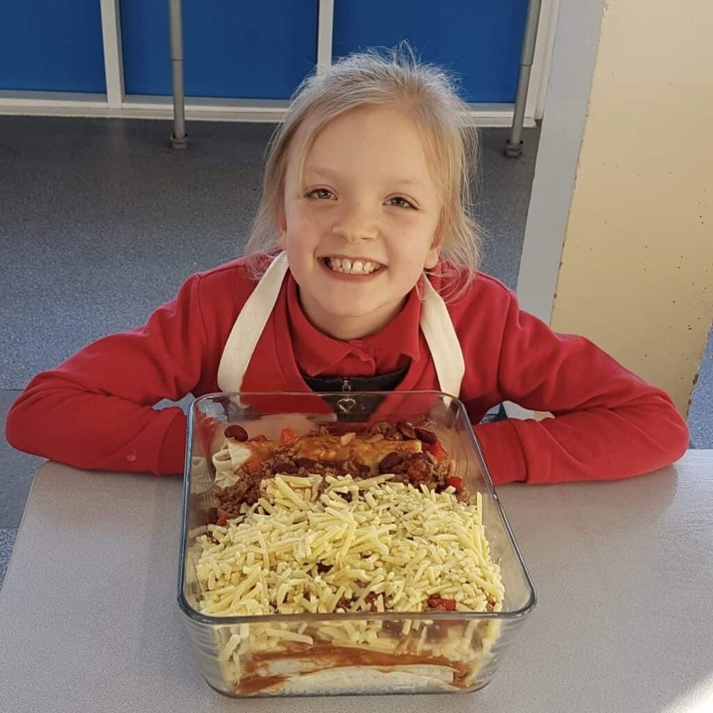 Child smiling with beef enchiladas