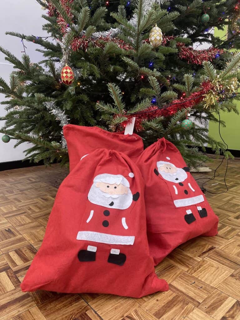 Two santa sacks in front of a Christmas tree